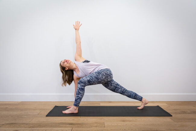 woman doing side angle yoga pose on a grey mat
