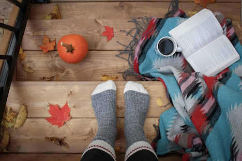 a person standing on stairs with a cosy blanket and a book nearby