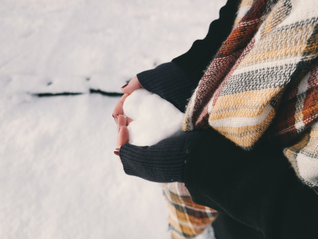 woman holding snow in the shape of a heart